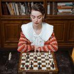 From Past to Present The Evolution of Iconic Board Games, a woman sitting in front of a chess board