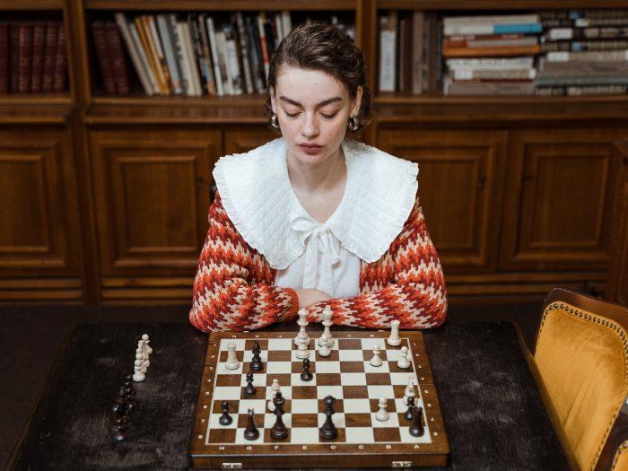 From Past to Present The Evolution of Iconic Board Games, a woman sitting in front of a chess board
